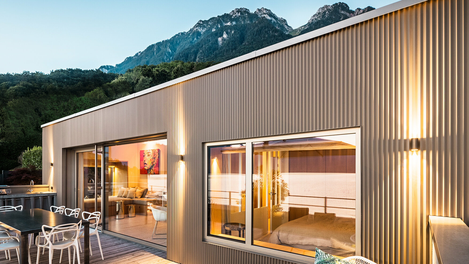 Pohľad na terasu a časť vnútra budovy večer.