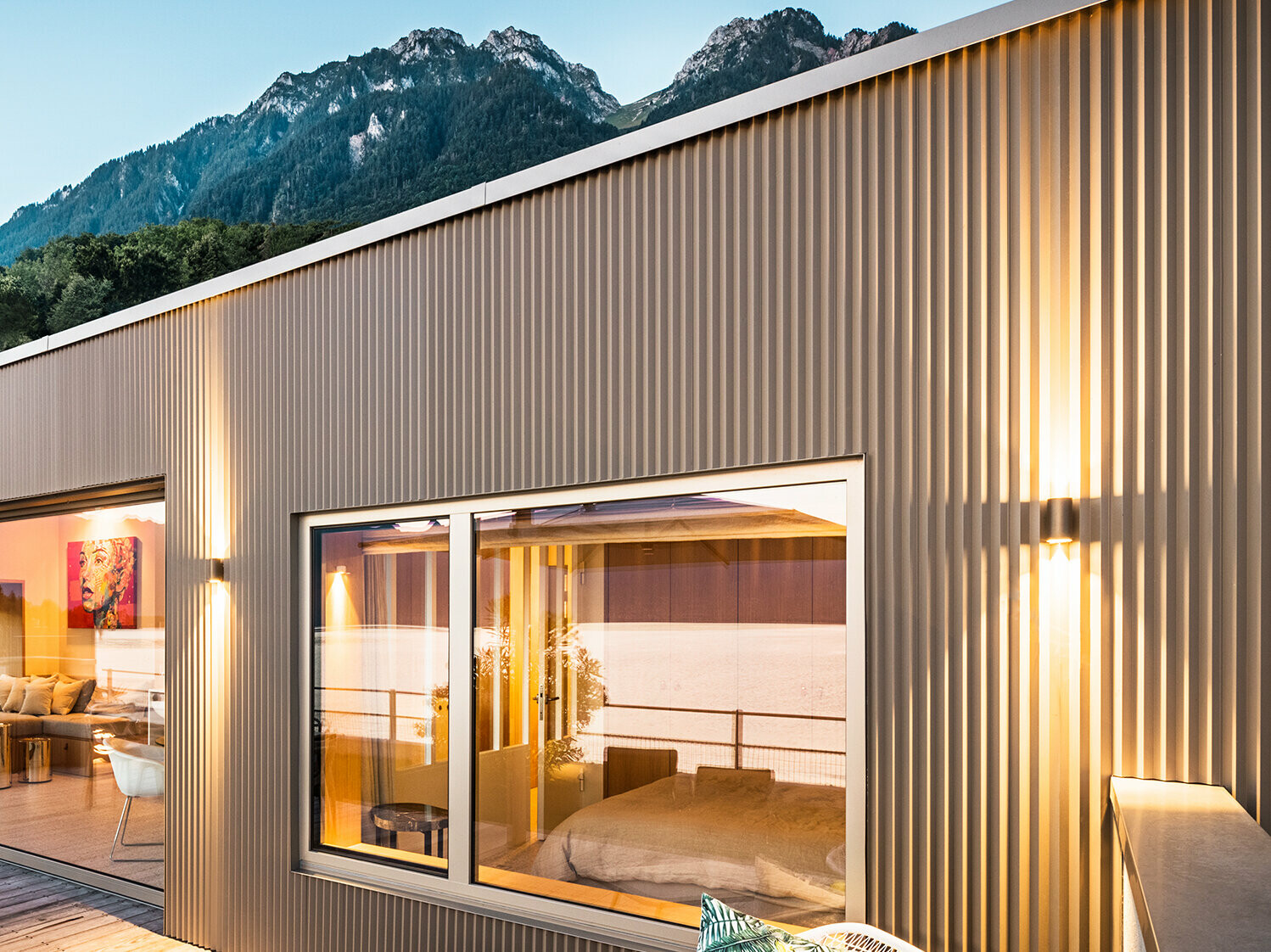 Pohľad na terasu a časť vnútra budovy večer.