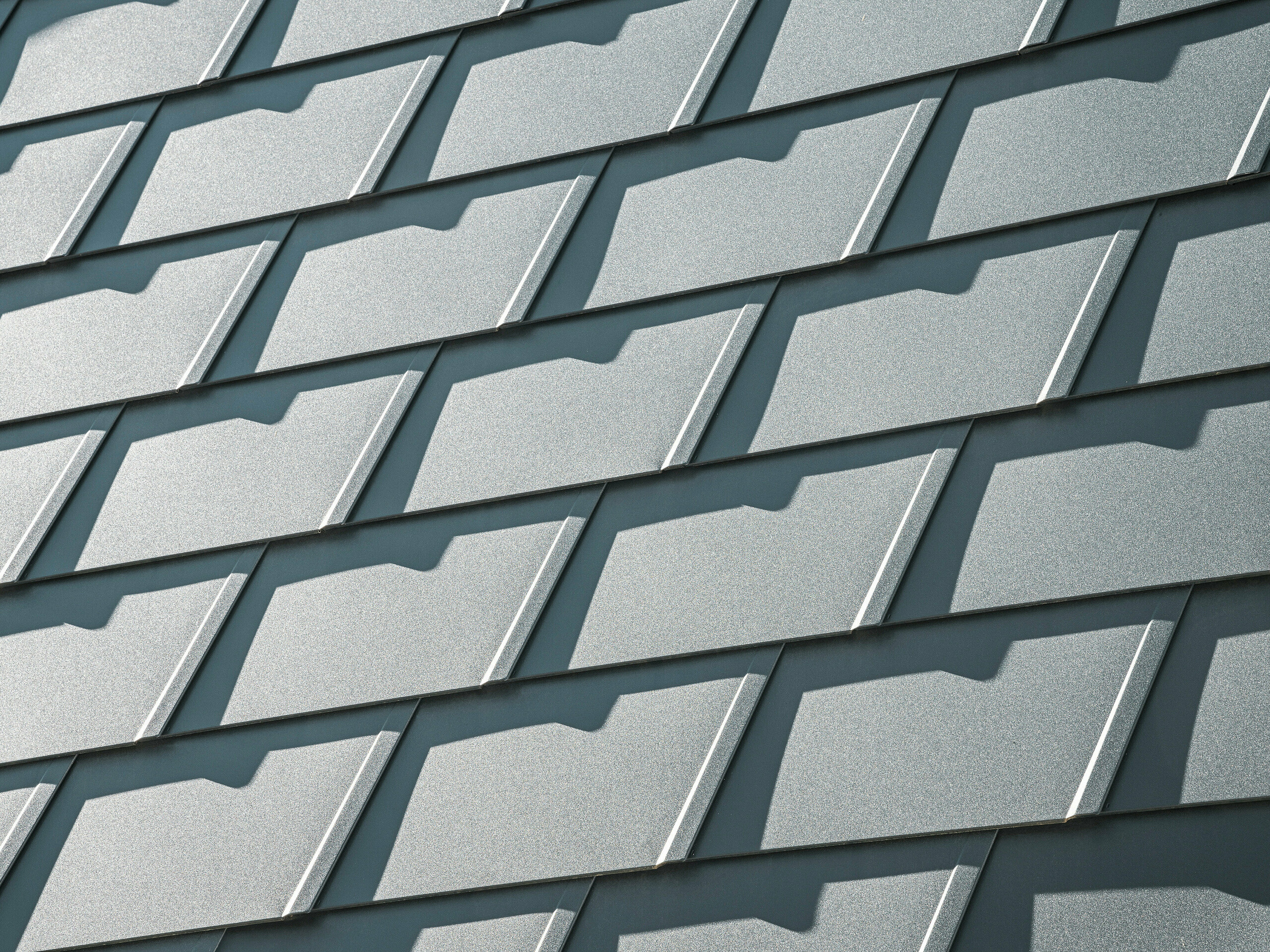 Detailný pohľad na strešné šindle PREFA DS.19 v antracitovej farbe P.10 na rodinnom dome v Mechernichu. Odolné hliníkové strešné šindle poskytujú optimálnu ochranu pred poveternostnými vplyvmi a zabezpečujú moderný, estetický dizajn strechy.