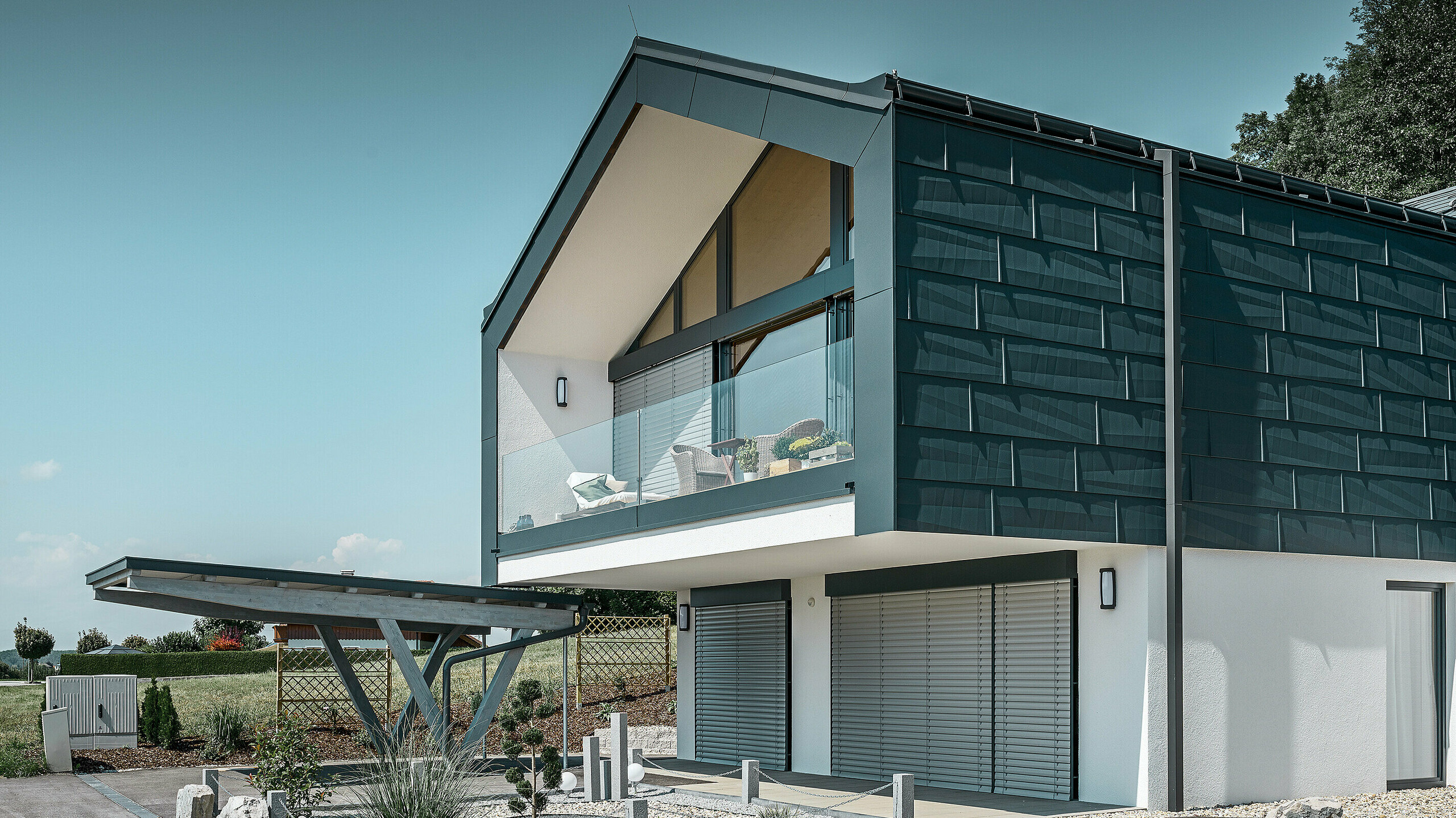 Fassadenverkleidung des Obergeschoßes mit dem PREFA Fassadenpaneel FX.12 in P.10 Anthrazit. Als Ablaufrohr dient das robuste PREFA Quadratrohr.