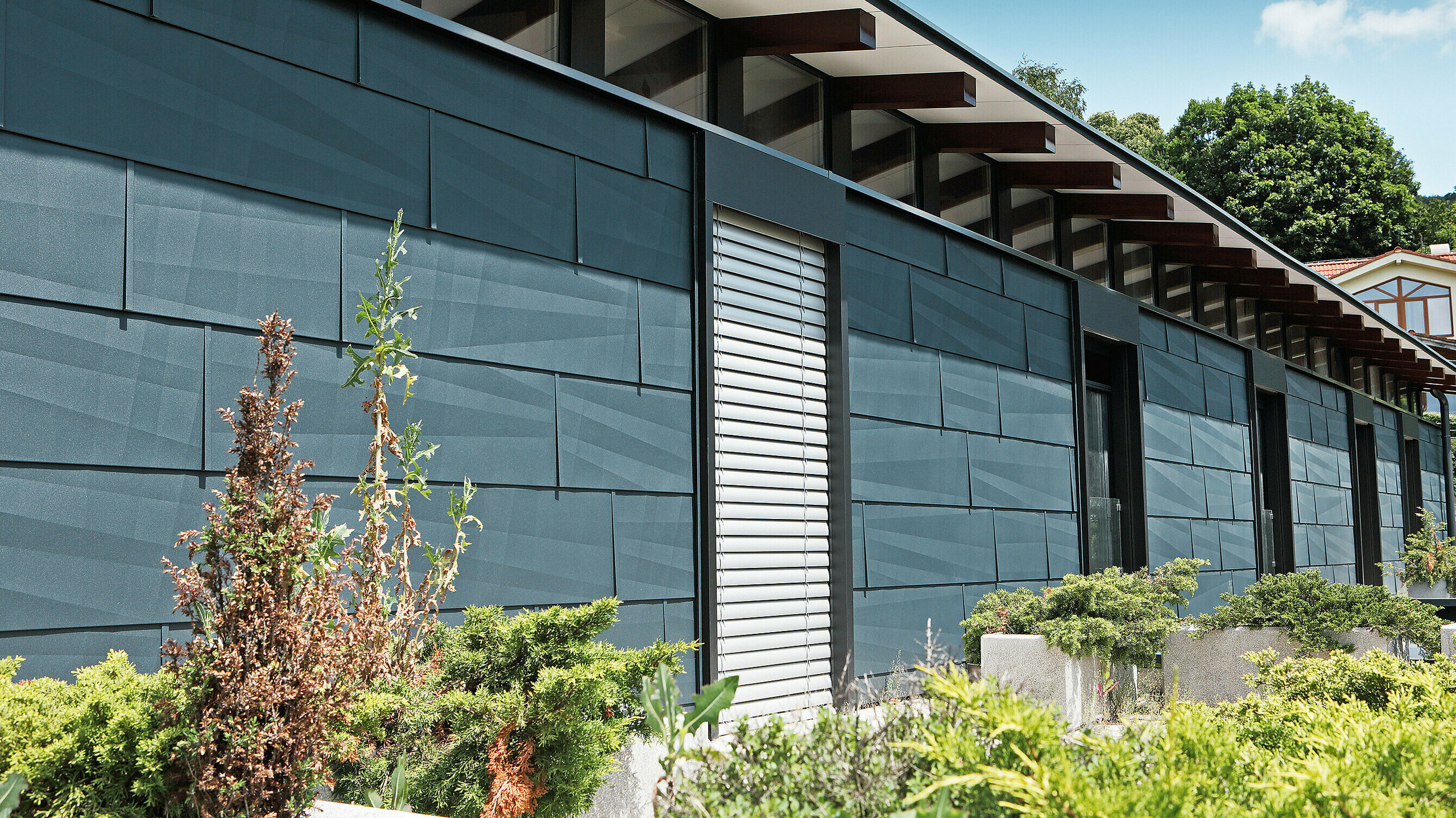 Moderne Wetterseite gestaltet mit dem Fassadenpaneel FX.12 in Anthrazit mit Garten.