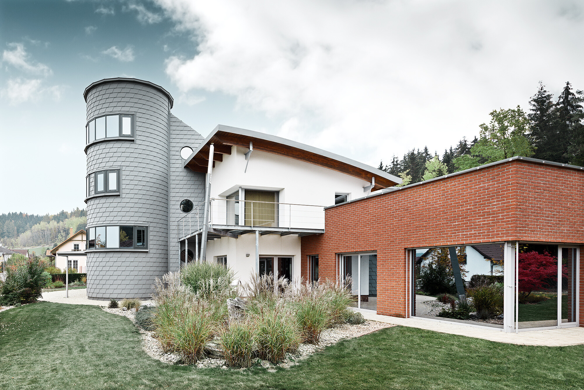 Rodinný dom s vežovou prístavbou, okrúhla veža je obložená s PREFA fasádnym šindľom vo farbe patina šedá 