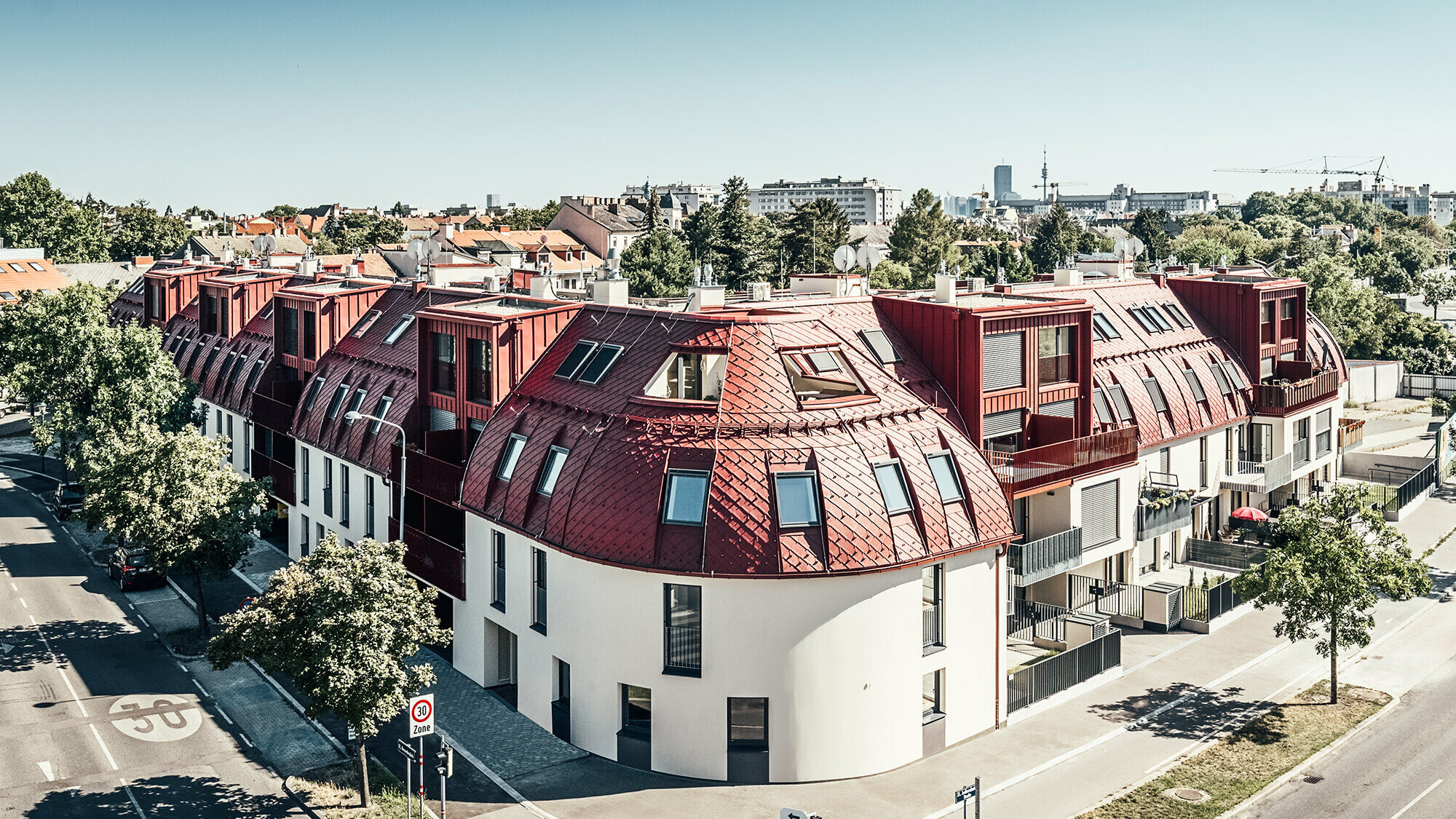 Pohľad na obytný komplex Schöneck 13 a zaoblenú strešnú krajinu, navrhnutú architektonickým ateliérom schneider+schumacher.