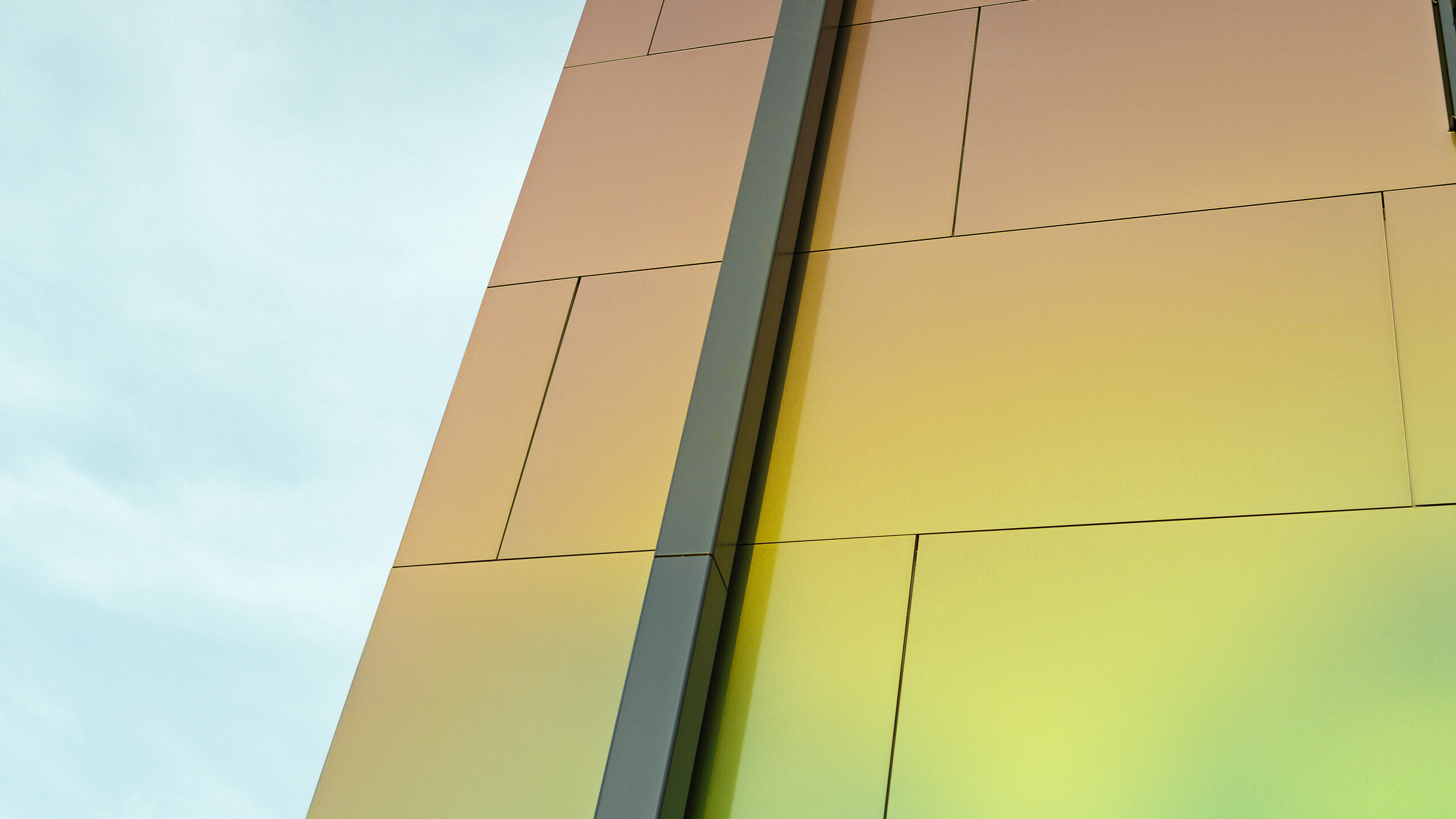 Roh moderného rodinného domu s modernými odtokovými rúrkami PREFA štvorcovými rúrkami na odvod vody z plochých striech. Fasáda je obložená hliníkovými kompozitnými doskami v žiarivej farbe „spring lake“.