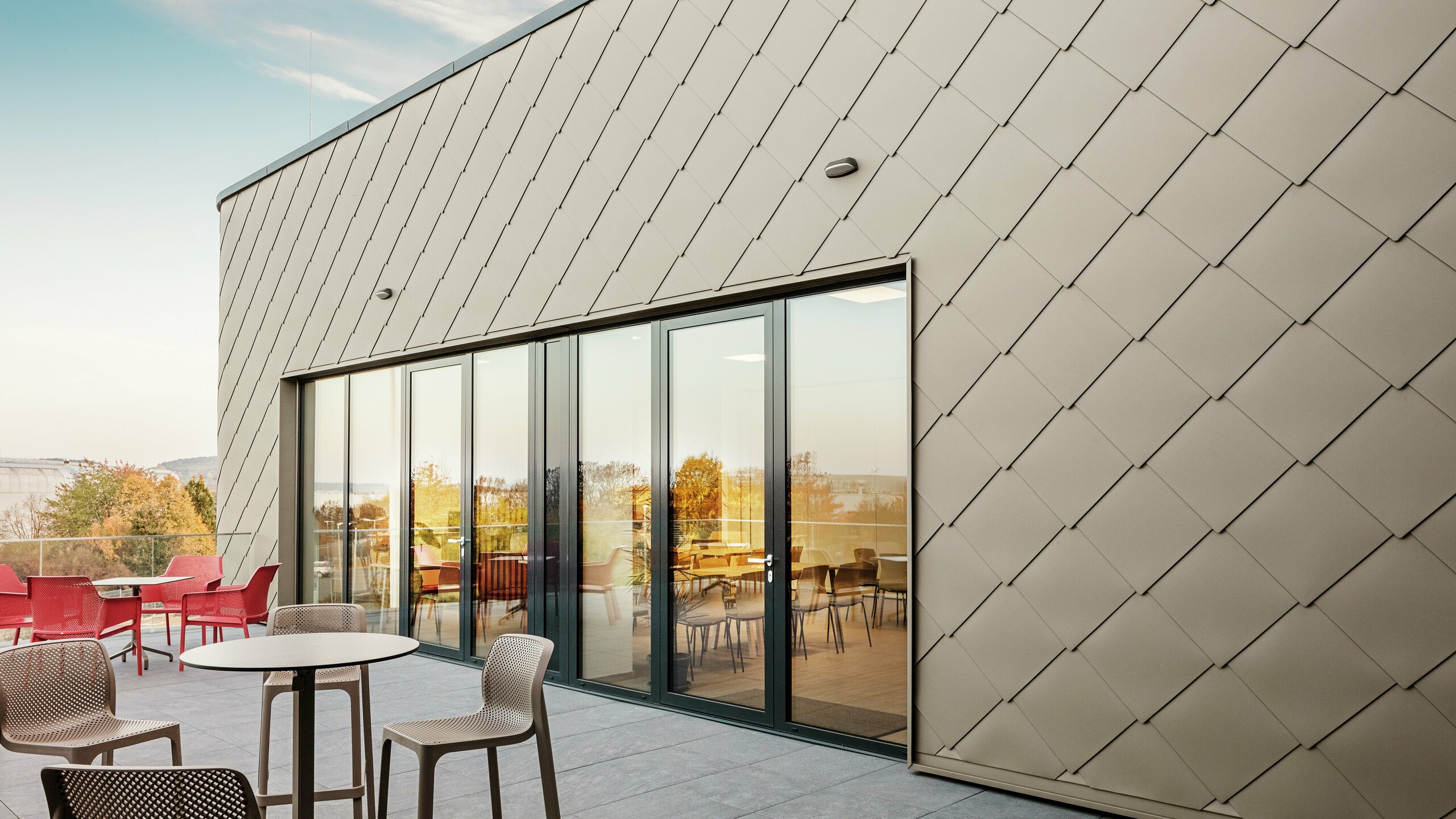 Fasádu nového sídla spoločnosti PREFA v maďarskom Törökbálinte charakterizujú elegantné P.10 prefa bronzové fasádne šablóny PREFA 44 × 44. Precízne položená hliníková fasáda poskytuje moderný, dynamický vzhľad a zároveň poskytuje maximálnu ochranu pred poveternostnými vplyvmi. Veľkorysé presklené priečelie spája vnútorné a vonkajšie priestory a vytvára svetlú a príjemnú atmosféru na priestrannej terase.