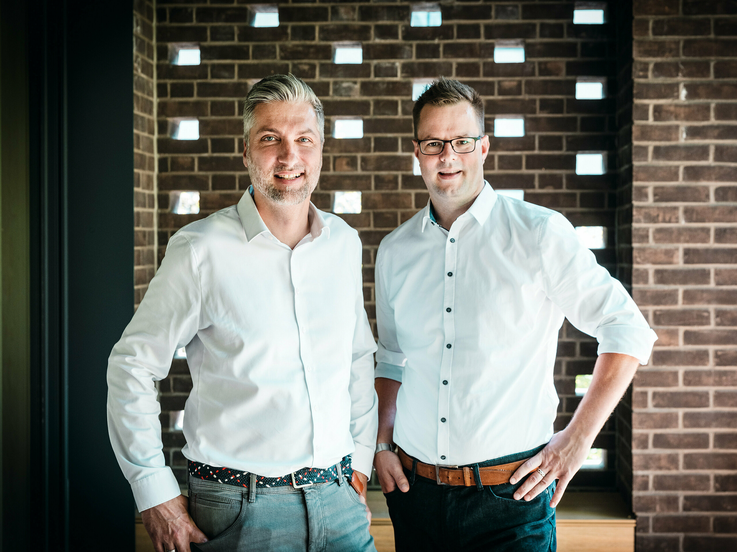 Architektonický tím z A Fiúk Építész Stúdió stojí v modernom interiéri budapeštianskej viacgeneračnej vily, ktorá bola ocenená v rámci PREFARENZEN 2026. Pred charakteristickou tehlovou stenou prezentujú presný jazyk materiálov a tvarov svojho projektu, ktorý je definovaný kubickou strechou z hliníka PREFALZ v odtieni P.10 antracit. Scéna zdôrazňuje architektonickú odbornosť, vysokú kvalitu spracovania a premyslený výber materiálov, pri ktorom hliník PREFA presviedča svojou trvácnosťou, výrazným dizajnom a technickou precíznosťou.