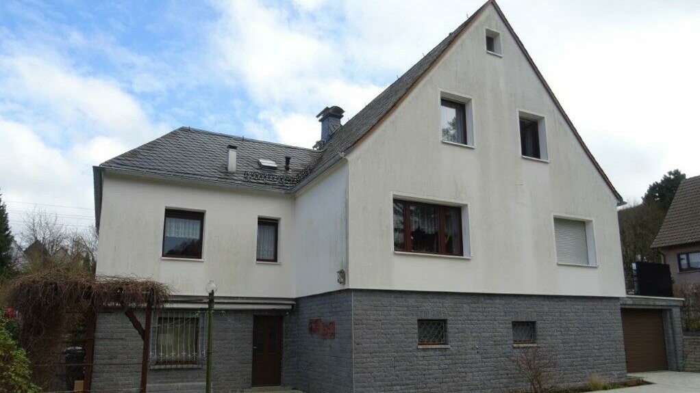 Wohnhaus mit alter Putzfassade in Weiß mit grauem Klinker.